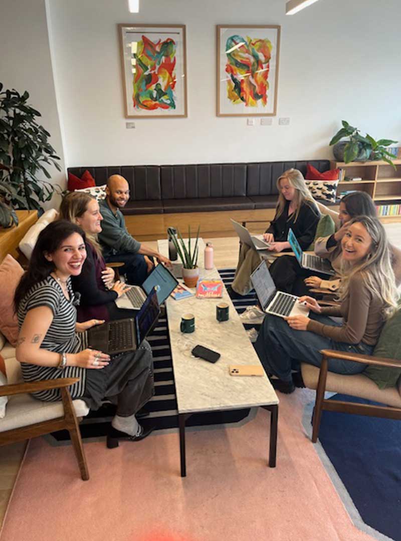 Team collaborating during a business meeting with laptops and notebooks.