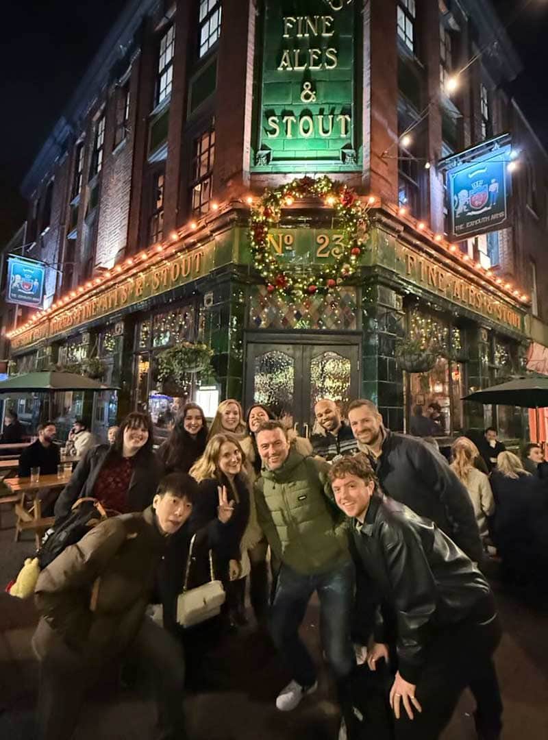 Group of people enjoying an evening outside a pub decorated for Christmas, with Onyx branding visibl.