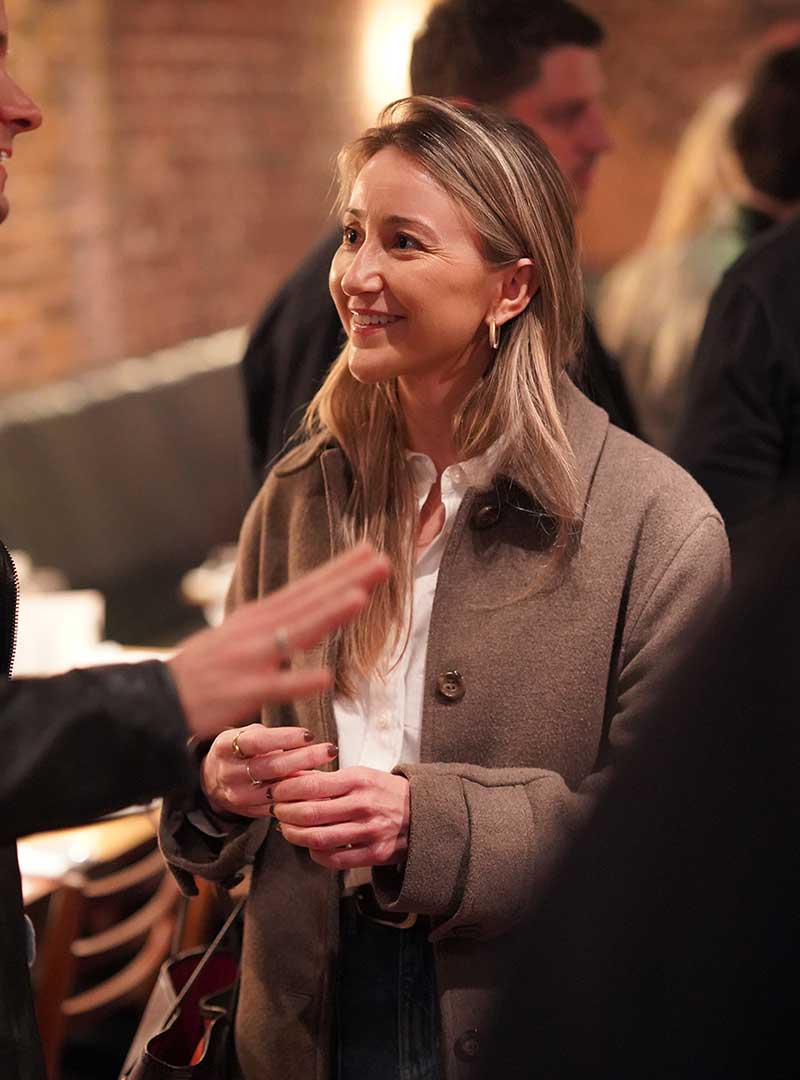 Woman speaking at an event, engaging with attendees in a professional setting.